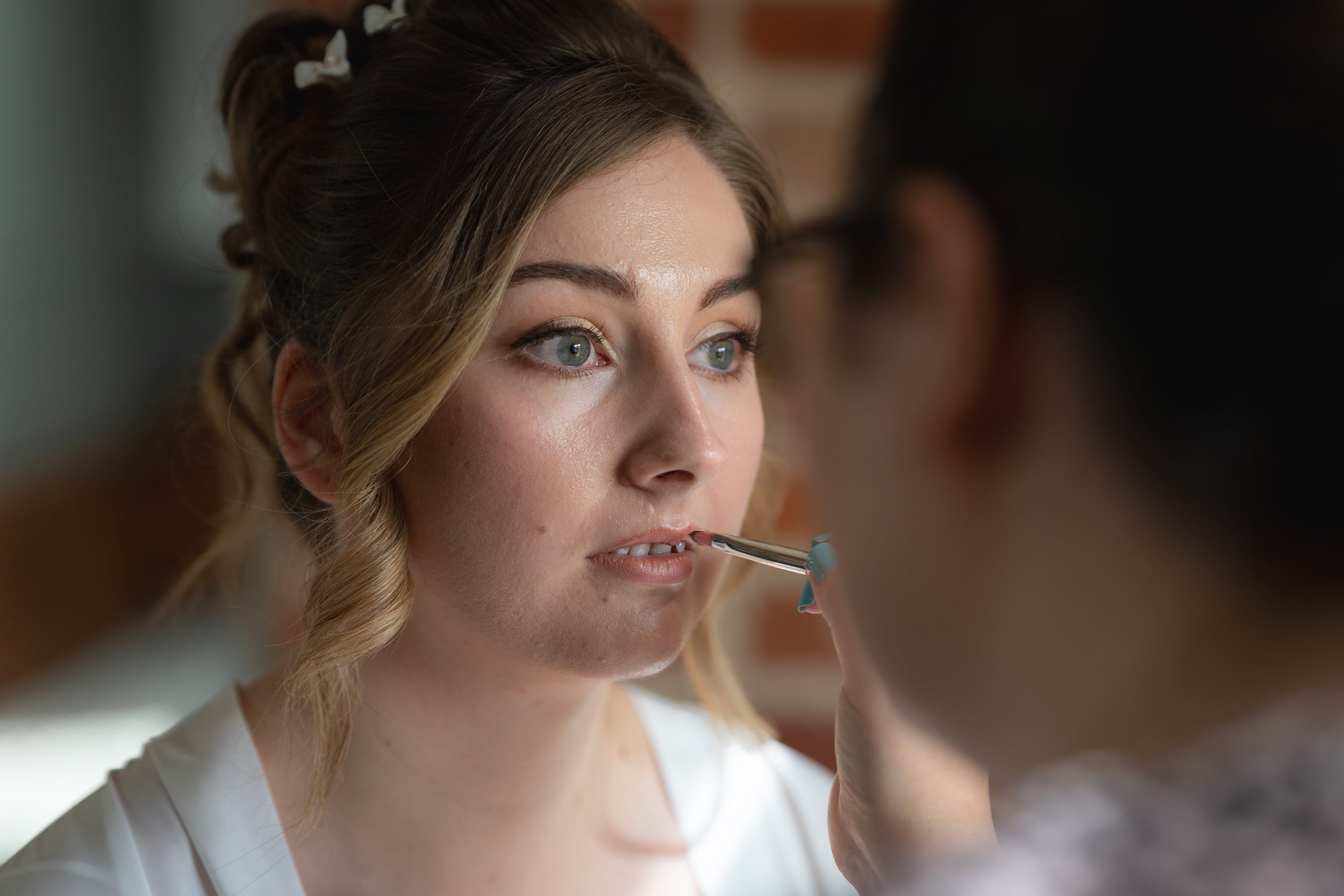 A bride wearing natural makeup having final touch ups to her look for her wedding at Channels Estate in Chelmsford, Essex.