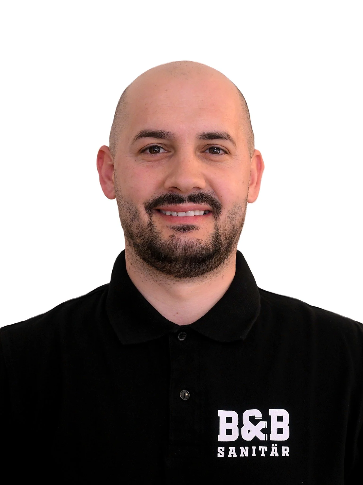 Porträt eines Mannes mit dunklem Bart, kurzen Haaren, schwarz gepoltem Polo mit Logo 'B&B SANITÄR' auf weißem Hintergrund.