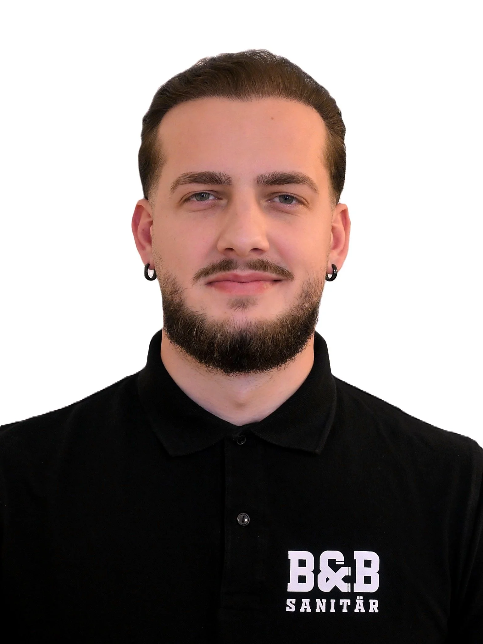 Porträt eines jungen Mannes mit dunklem Bart, schwarzen Ohrringen, dunklem Hemd mit Firma B&B Sanitär