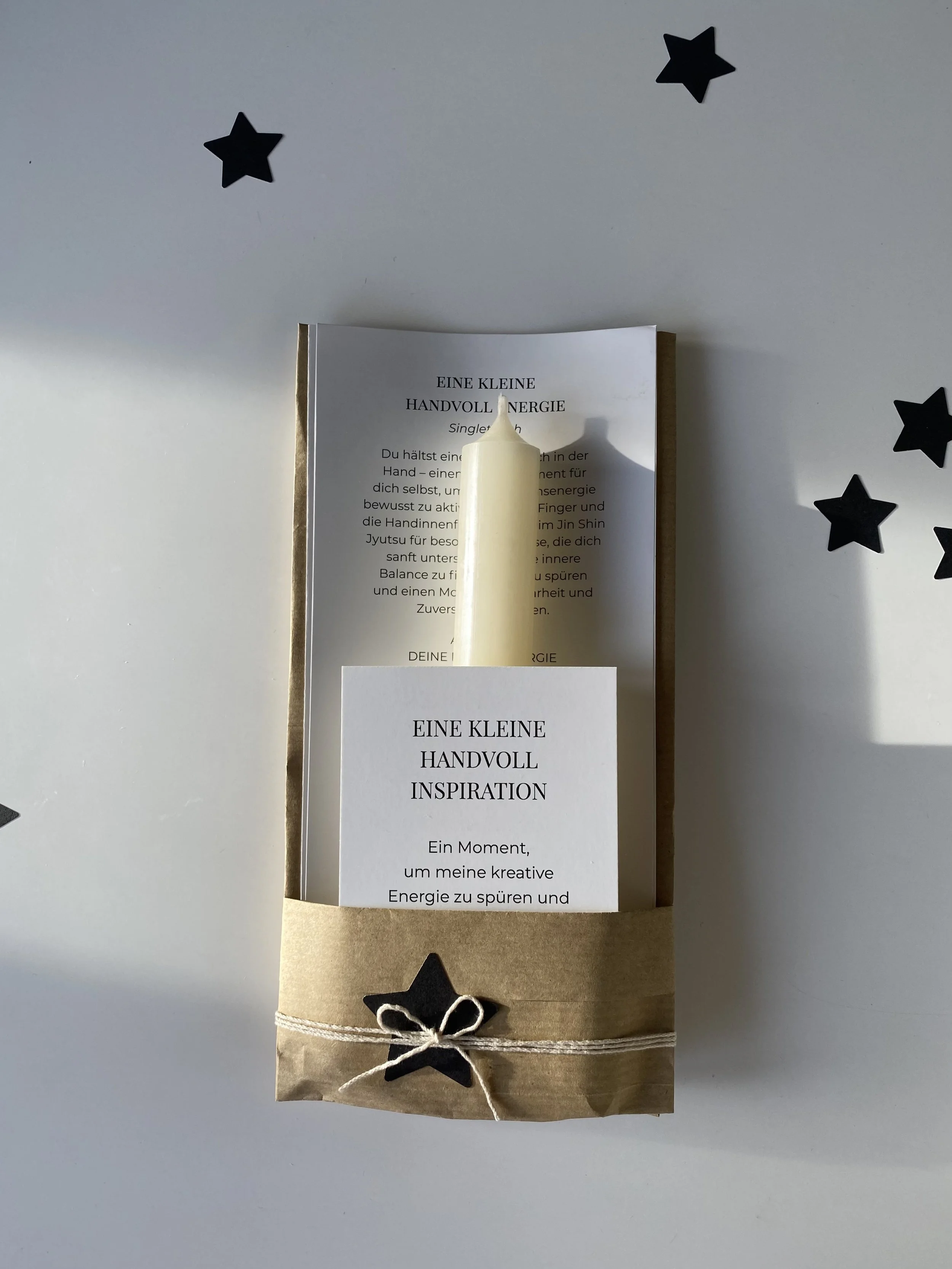 Geschenk mit Kerze, Karten und Sternaufklebern auf weißem Hintergrund.