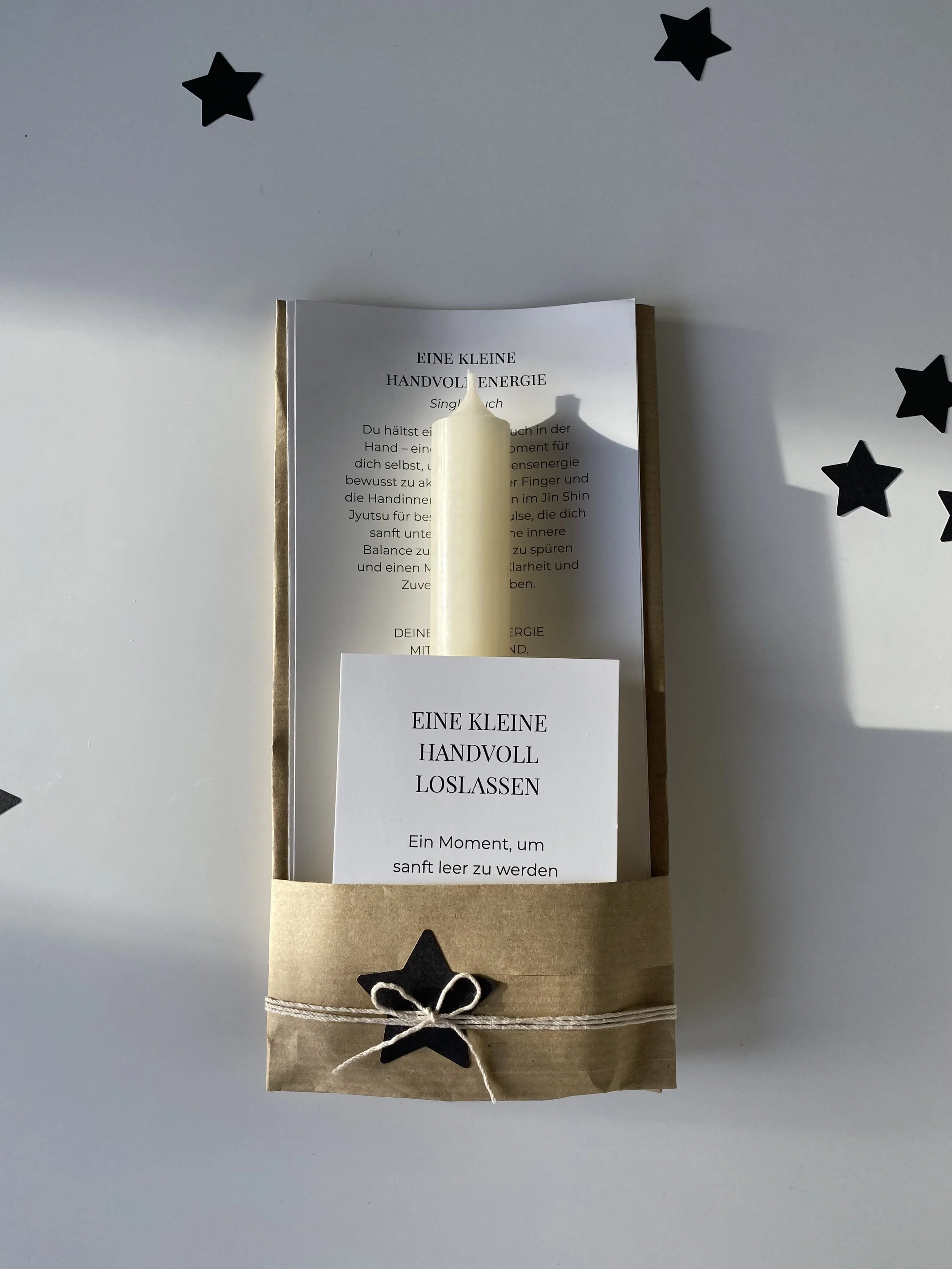 Geschenk mit Kerze, schwarzem Stern, Papier, handgeschriebenem Text und Verpackung mit Schnur und Sternaufkleber