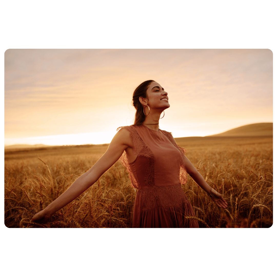A woman stands open armed in a field with sunshine after learning how to feel your feelings