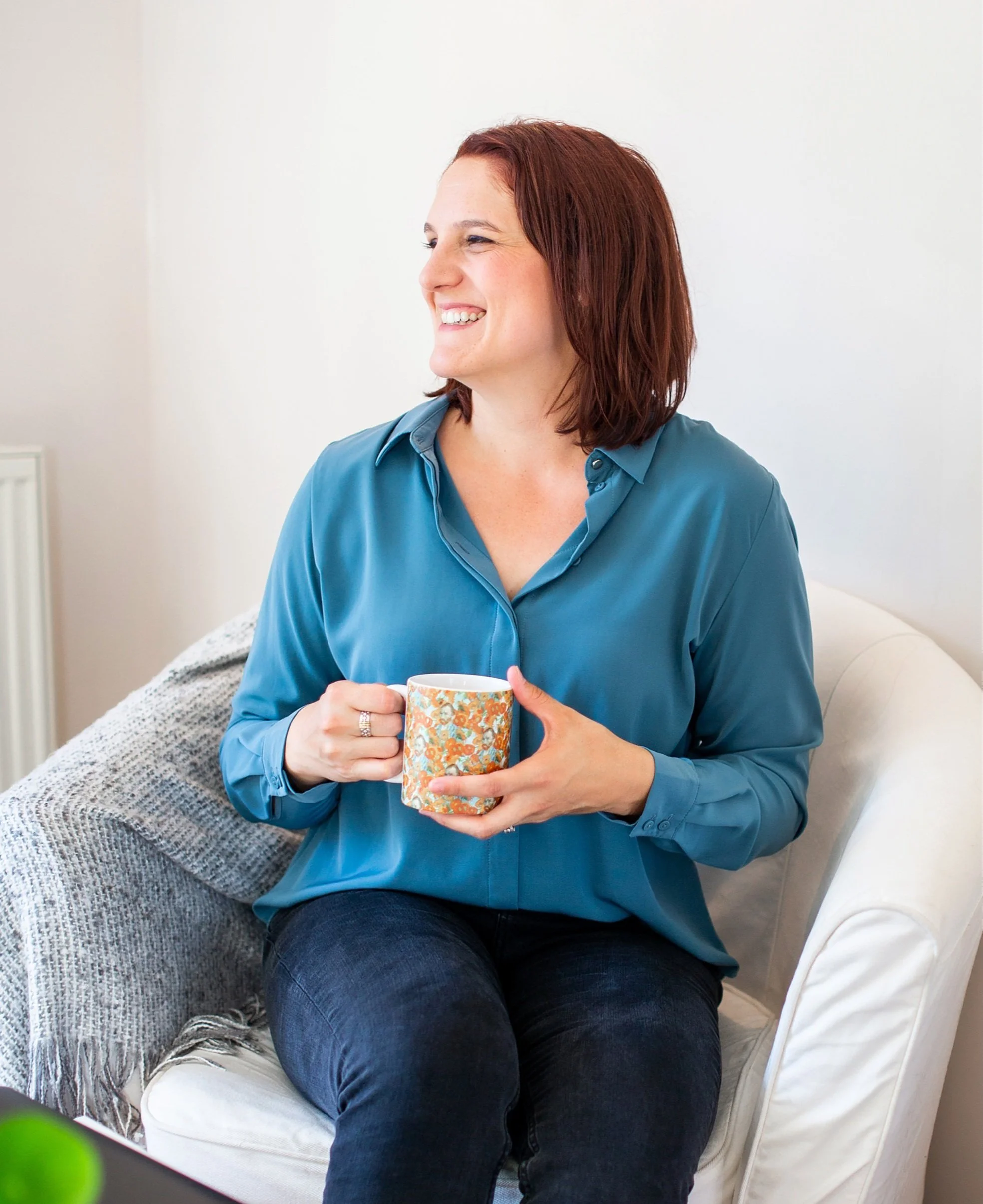 Erin a Depression Therapist Houston smiling brightly while holding a coffee mug — creating a warm, welcoming space in depression therapy.