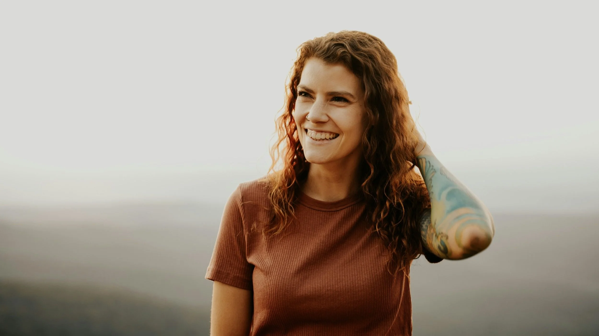 A young woman with curly hair smiles preparing for EMDR for Anxiety
