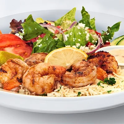 an image of the grilled shrimp feast showing grilled shrimp atop a bed of rice with a side greek salad