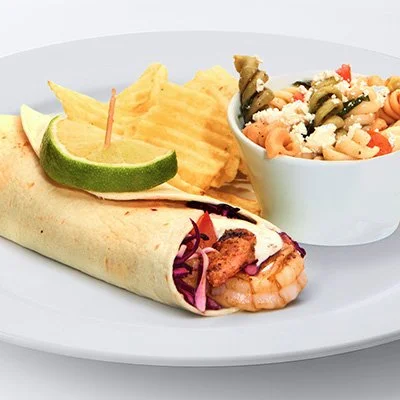 a photo of a taziki's shimp taco - grilled shrimp with crunchy slaw, spicy herb sauce, and diced tomatoes in a flour tortilla, topped with a lime. Served with chips and choice of a homemade side.