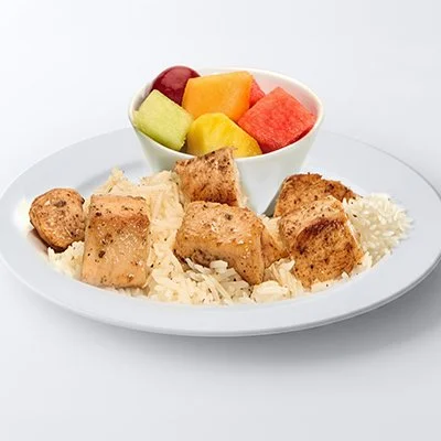a photo of the Child's Feast from Taziki's showing a white plate topped with bites of grilled chicken atop a bed of basmati rice and a side dish of fresh cut fruit