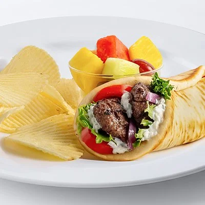 Photo of the Turkish Meatball Gyro on a plate with a side of potato chips and fresh cut fruit