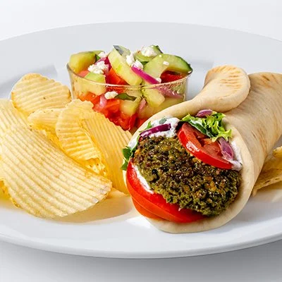 A photo of the baked falafel gyro from Tazikis with a side of cucumber tomato salad and potato chips