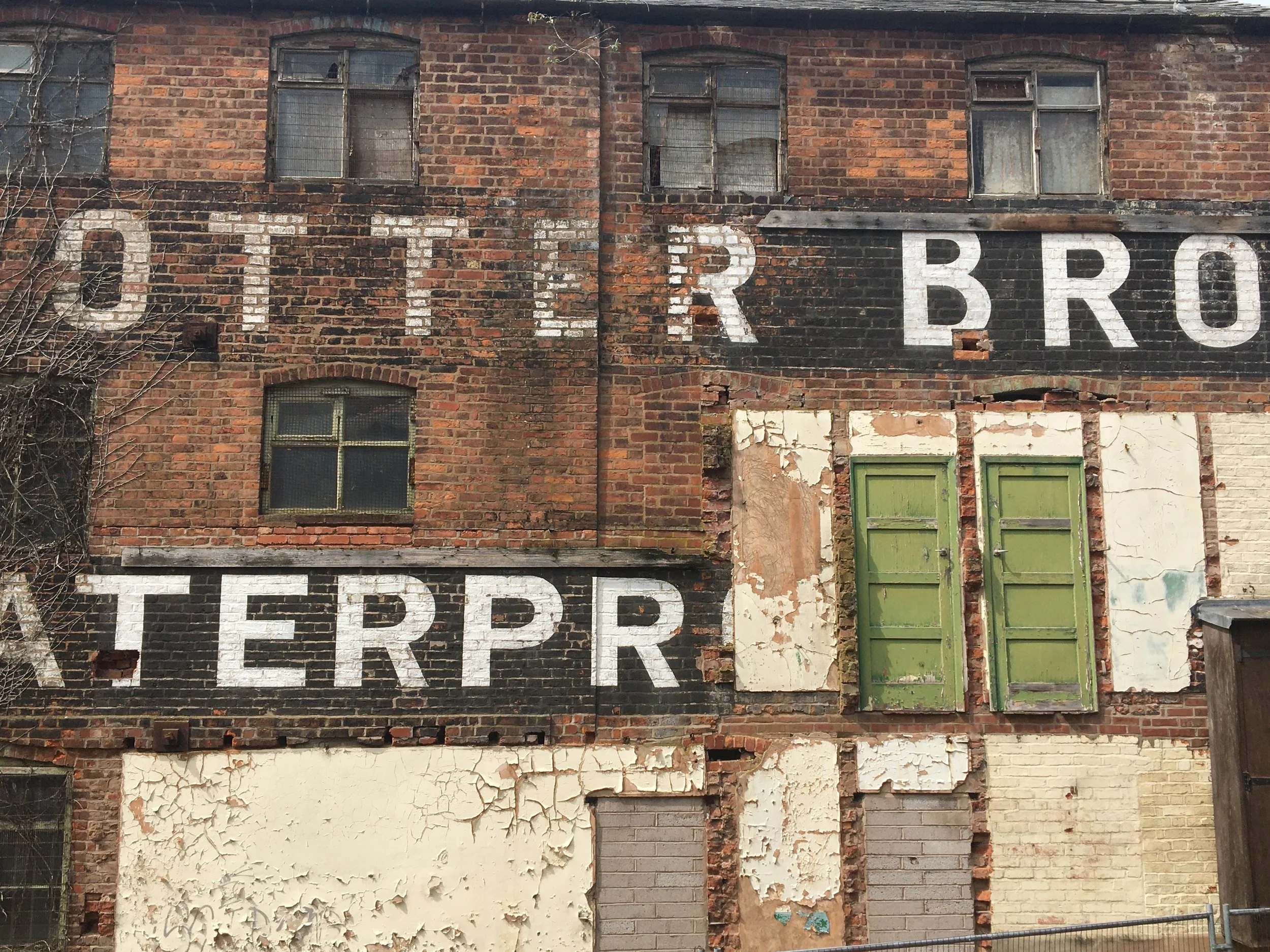 Historic industrial brick building facade showing paint failure, masonry decay and weathering assessed during condition survey