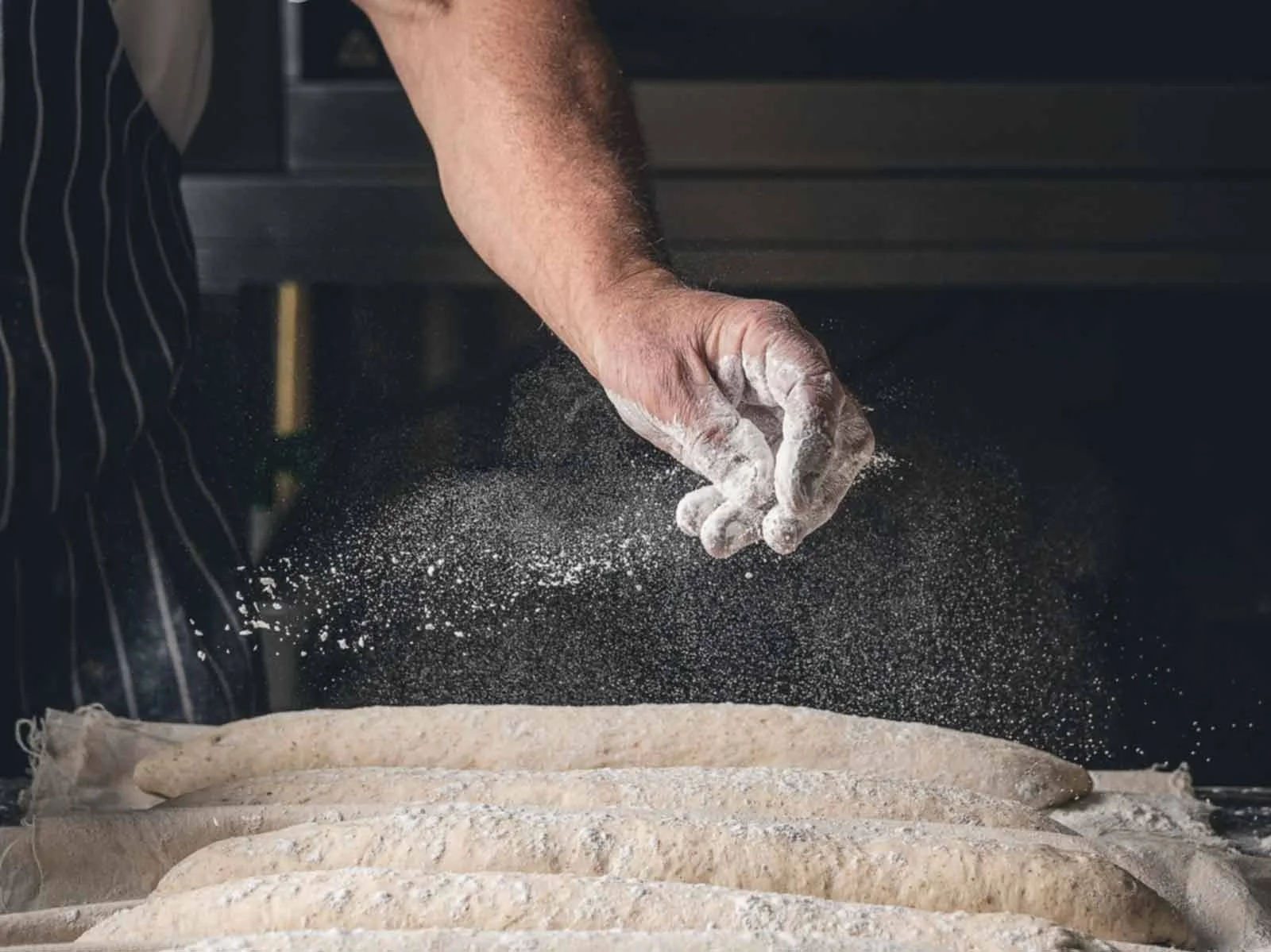 baker-sprinkling-flour-on-bread-dough.jpg
