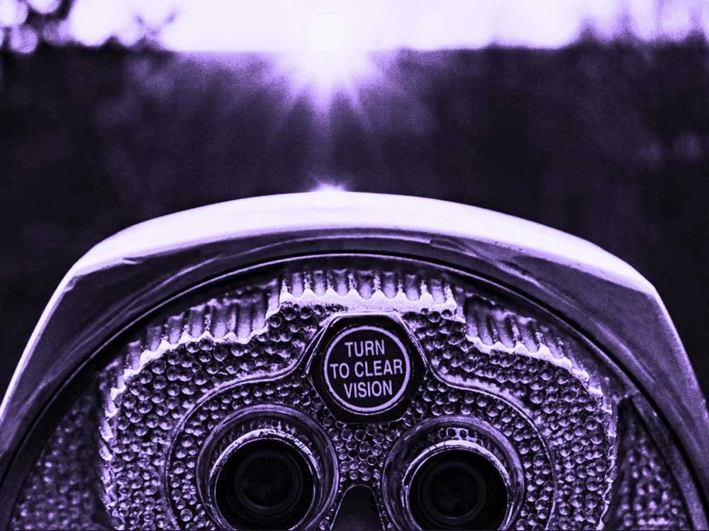 A close-up of a purple-tinted, coin-operated viewer with the words "TURN TO CLEAR VISION" on it.