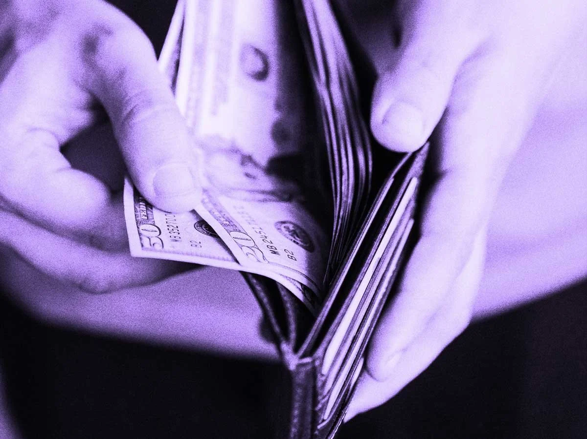 Hands holding a wallet filled with US dollar bills.