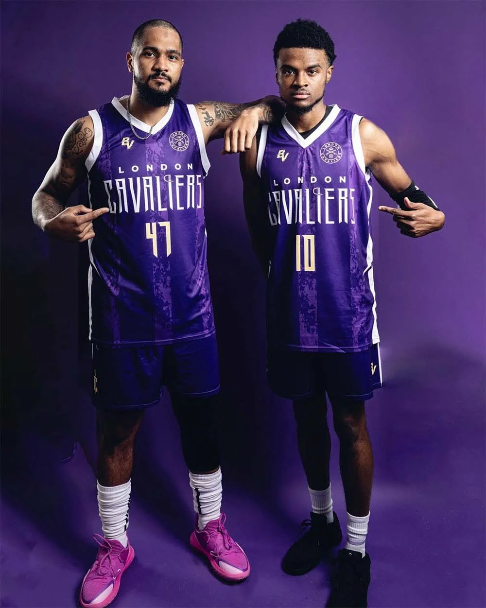 Two basketball players in purple London Cavaliers jerseys pose against a purple background.