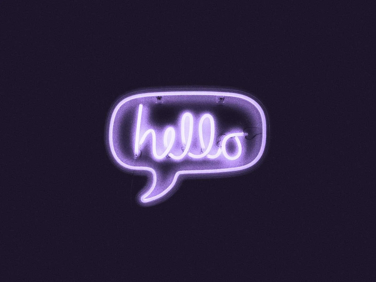 A purple neon sign shaped like a speech bubble displays the word "hello".
