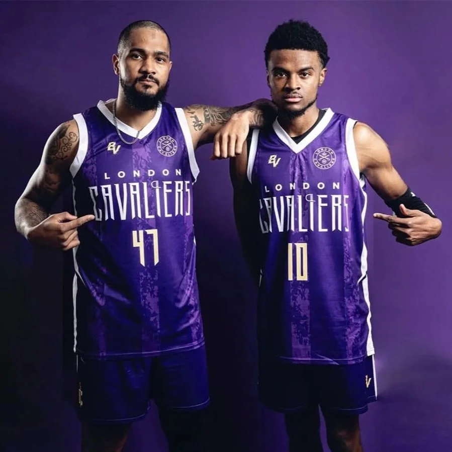 Two basketball players in purple London Cavaliers jerseys are posing against a purple background, each pointing to their jersey numbers, 47 and 10.