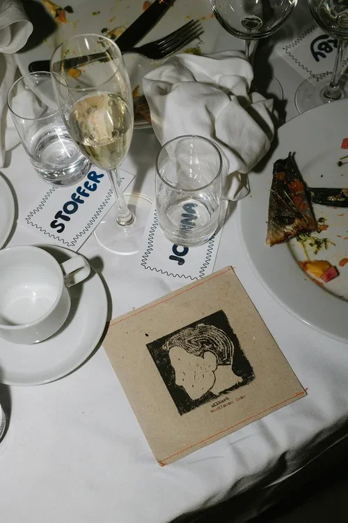 Close-up of a Marbella wedding reception table after dinner with handwritten name cards, champagne flute, illustrated menu card and half-eaten plates