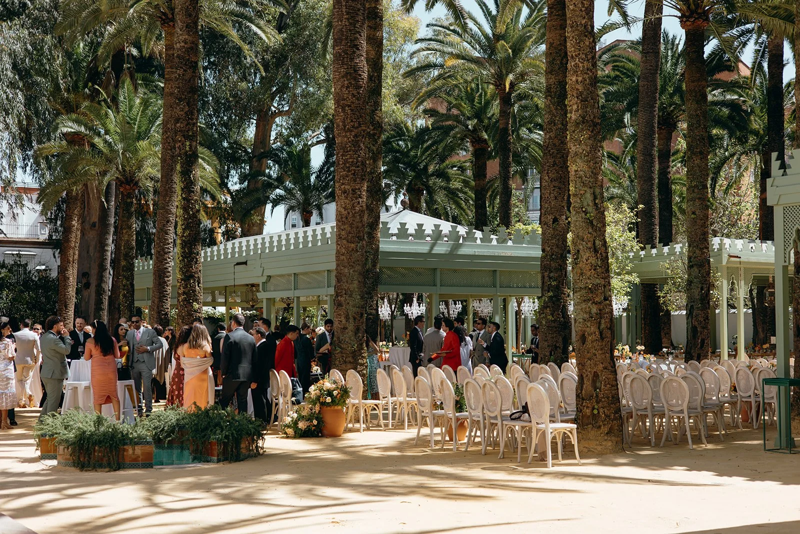 Guests chatting in a palm tree lined garden after a Marbella wedding ceremony