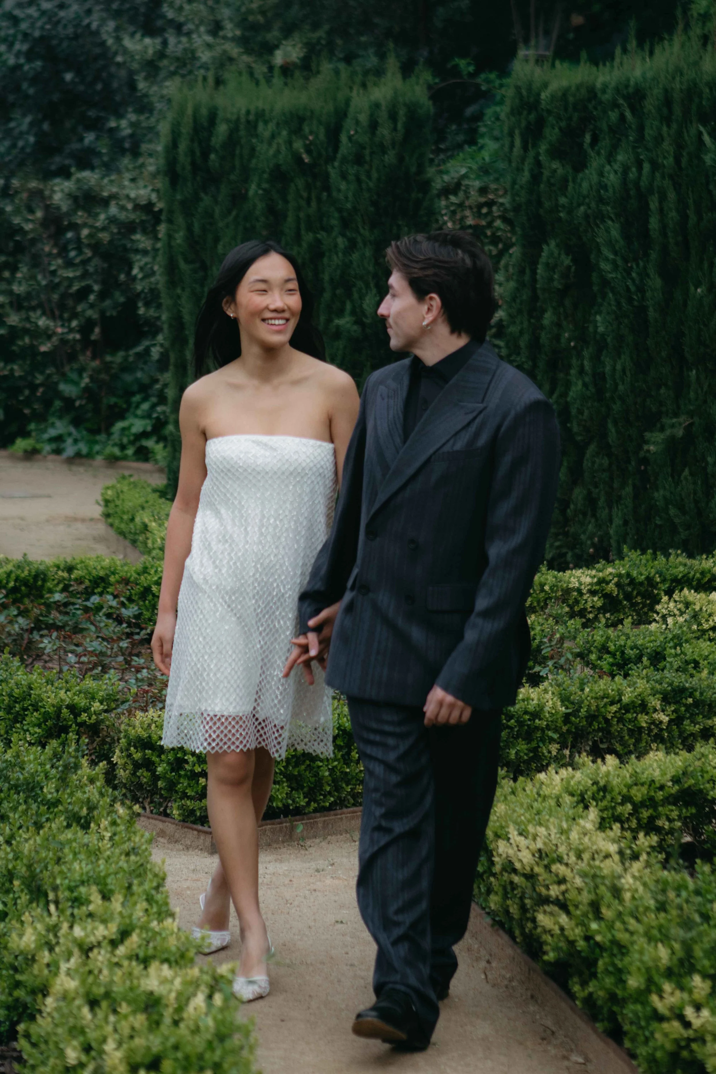 Smiling couple walking through a formal garden on their wedding day