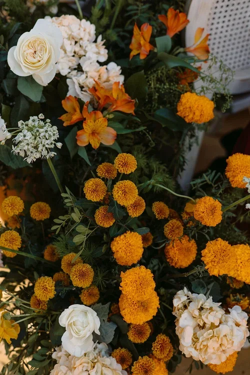 Close-up of lush wedding ceremony floral arrangement with golden marigolds, orange alstroemeria, white garden roses and hydrangea, luxury wedding florist photography Malaga Andalusia