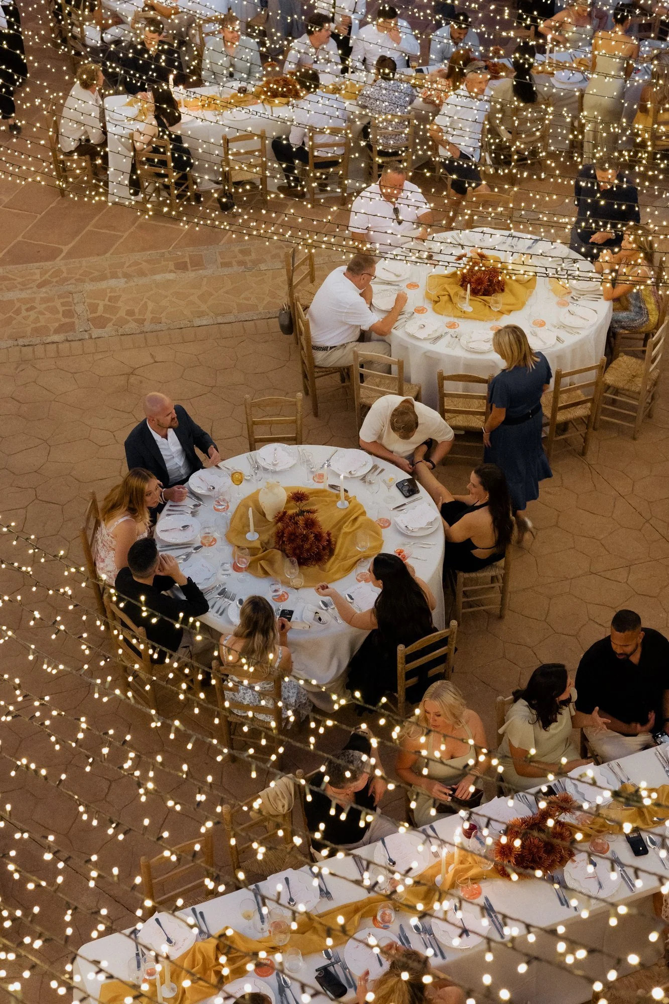 Aerial view of outdoor evening wedding reception with fairy lights and guests seated at round tables in Malaga