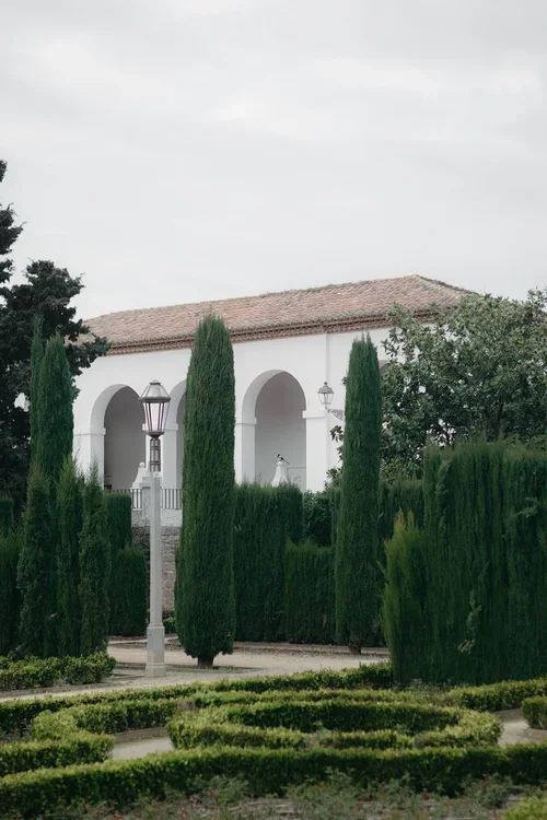 White Moorish-style pavilion with arched colonnades surrounded by tall Italian cypress trees and formal box hedging at a Malaga wedding venue