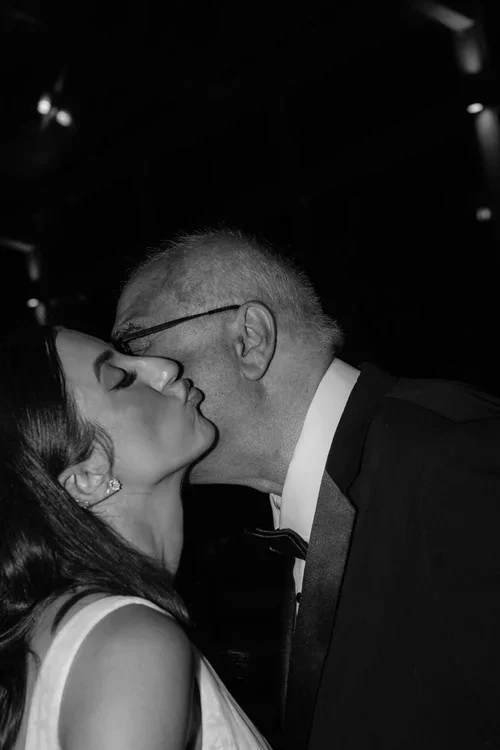 Emotional black and white close-up of a father kissing his bride daughter on the cheek