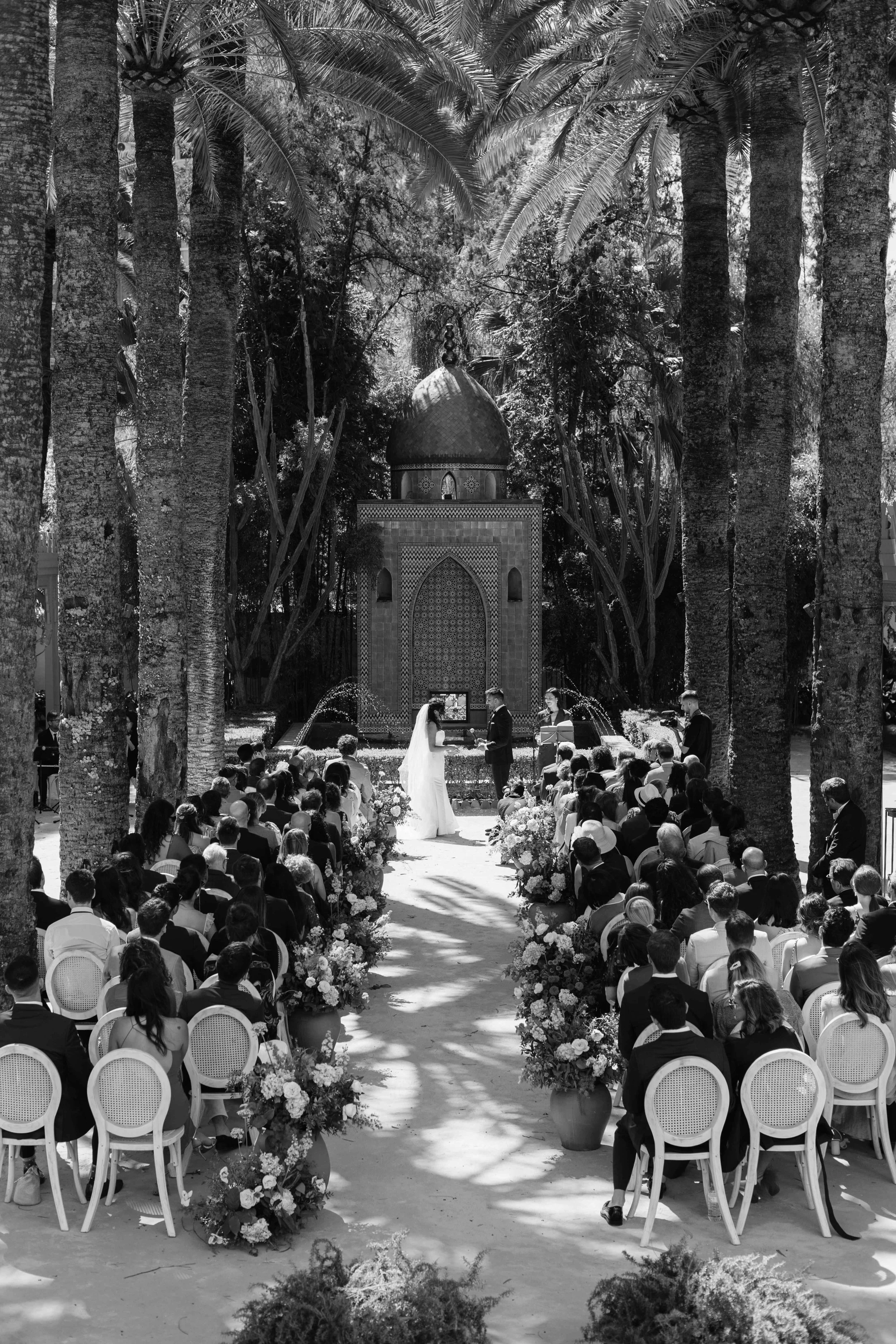Outdoor wedding ceremony beneath tall palm trees and a Moorish pavilion at a Marbella wedding venue