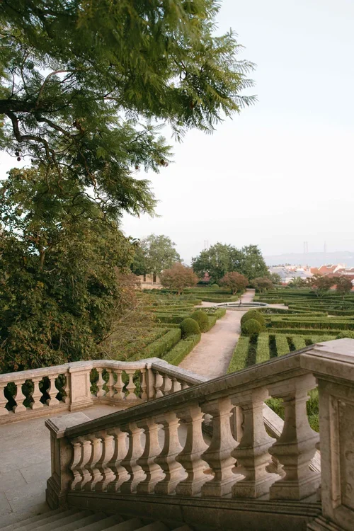 Wide stone balustrade staircase leading down to manicured formal box hedge in Lisbon