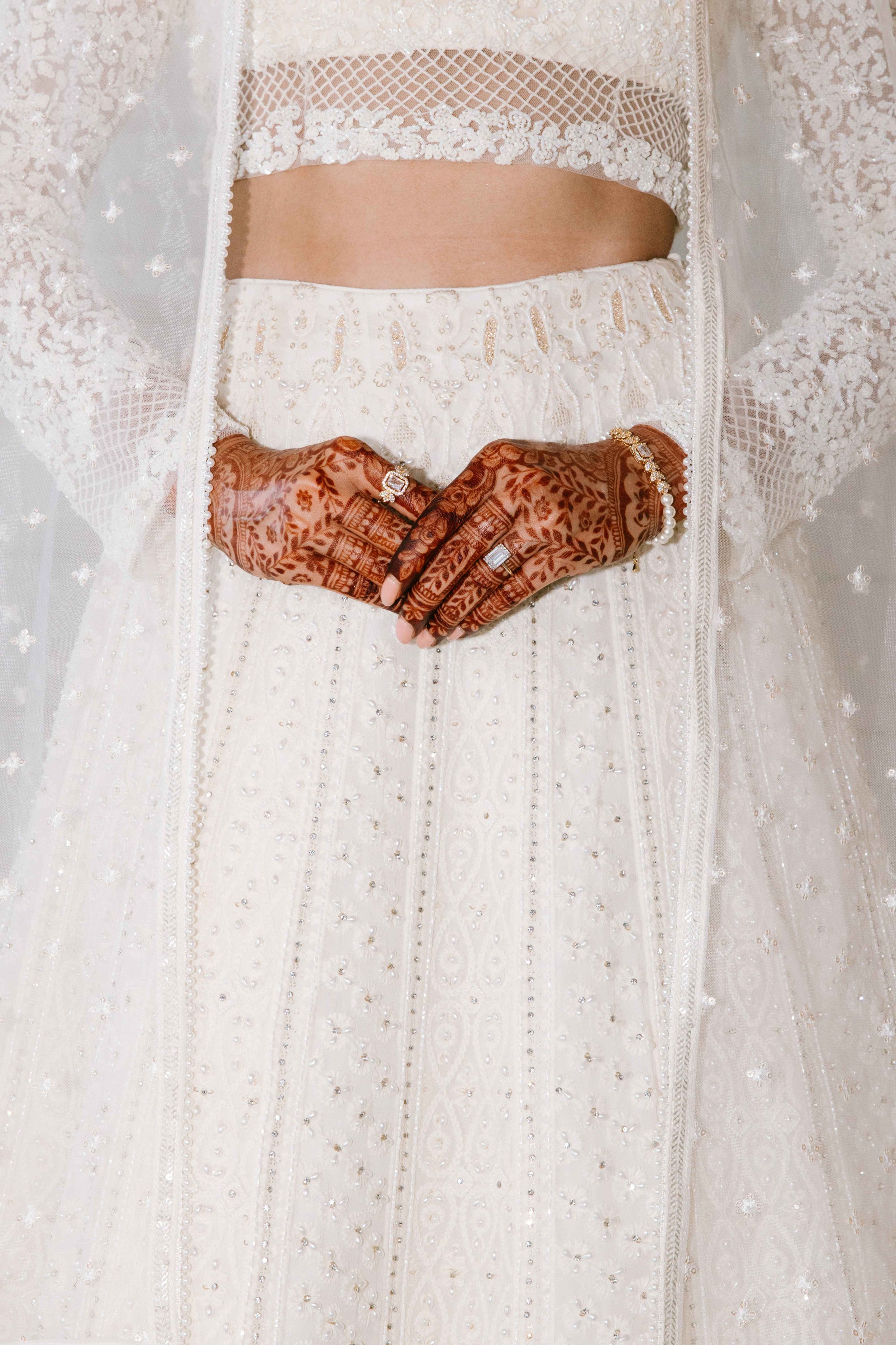 Close-up of a bride's henna-adorned hands with diamond rings