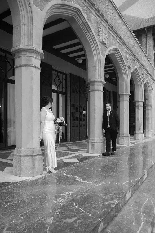 Bride and groom standing beneath a grand stone colonnade of arches on a marble floor at a historic wedding venue in Malaga