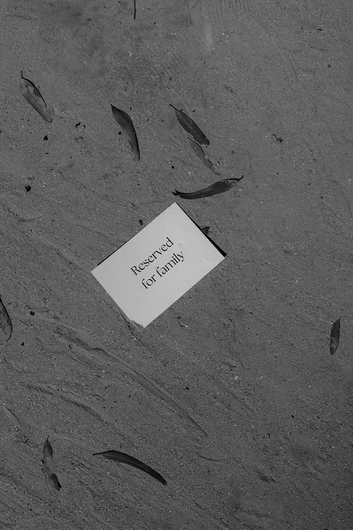 Small white card reading Reserved for family lying on sandy ground surrounded by fallen leaves at an outdoor Malaga wedding ceremony