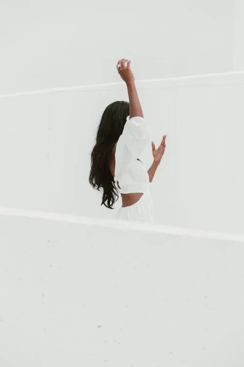 Bride twirling in white lace top and skirt against a bright white wall at a Malaga 