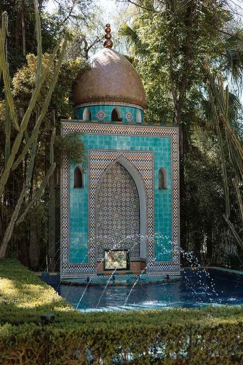 Ornate turquoise Moorish-style tiled fountain with a copper dome surrounded by palms and cacti in the grounds of a Seville wedding venue