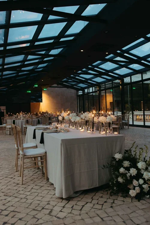 Atmospheric evening wedding reception with candlelit tables and white roses