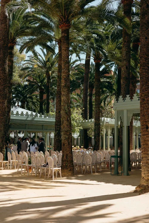 Outdoor wedding ceremony seating set up under tall palm trees in a Moorish pavilion garden in Malaga,