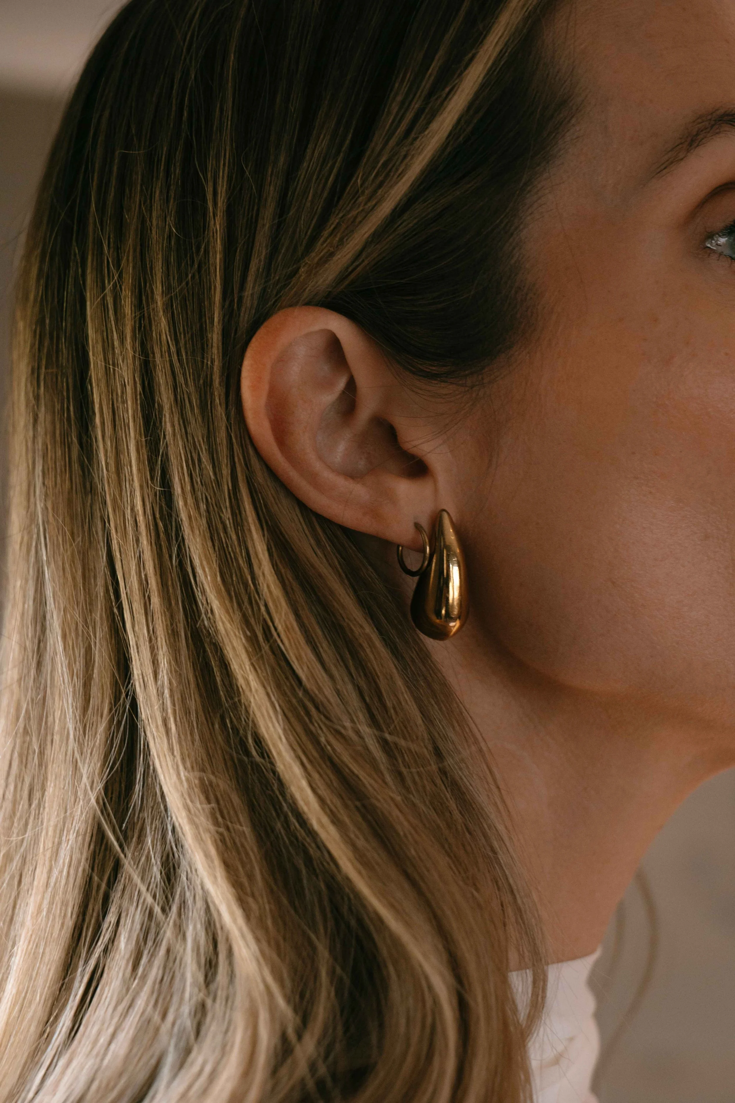 Close-up of bride wearing a chunky gold hoop earring with highlighted hair