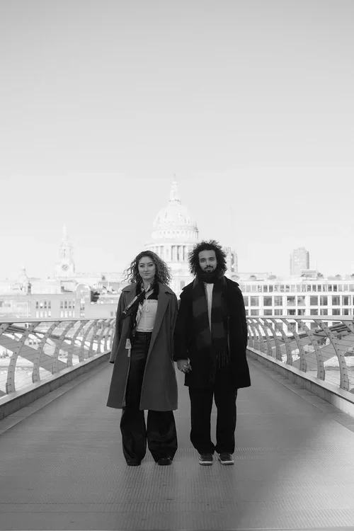 Stylish couple holding hands and standing on the Millennium Bridge in London with St Paul's Cathedral dome in the background