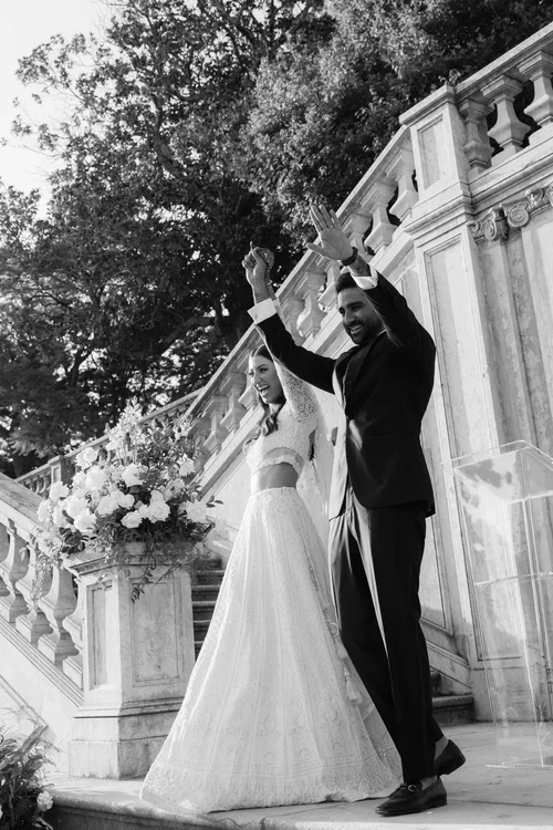 Just married couple celebrating with arms raised on ornate marble steps in Malaga