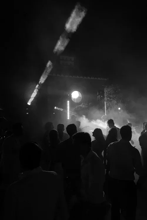Silhouetted wedding guests dancing under dramatic stage lighting and smoke at a Marbella evening wedding party