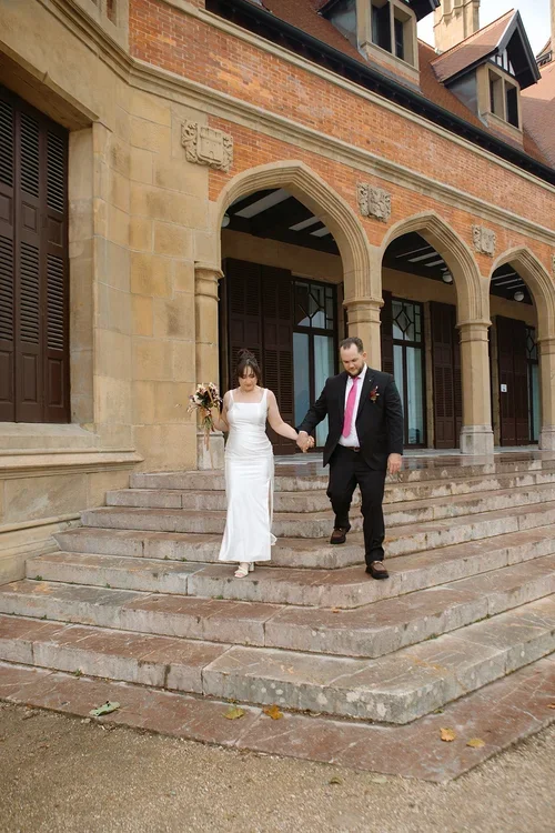 Bride and groom holding hands walking down the stone steps of a castle in Marbella