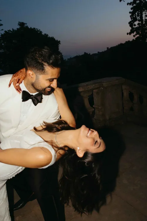 Groom dipping bride in a joyful moment at dusk in a manicured garden