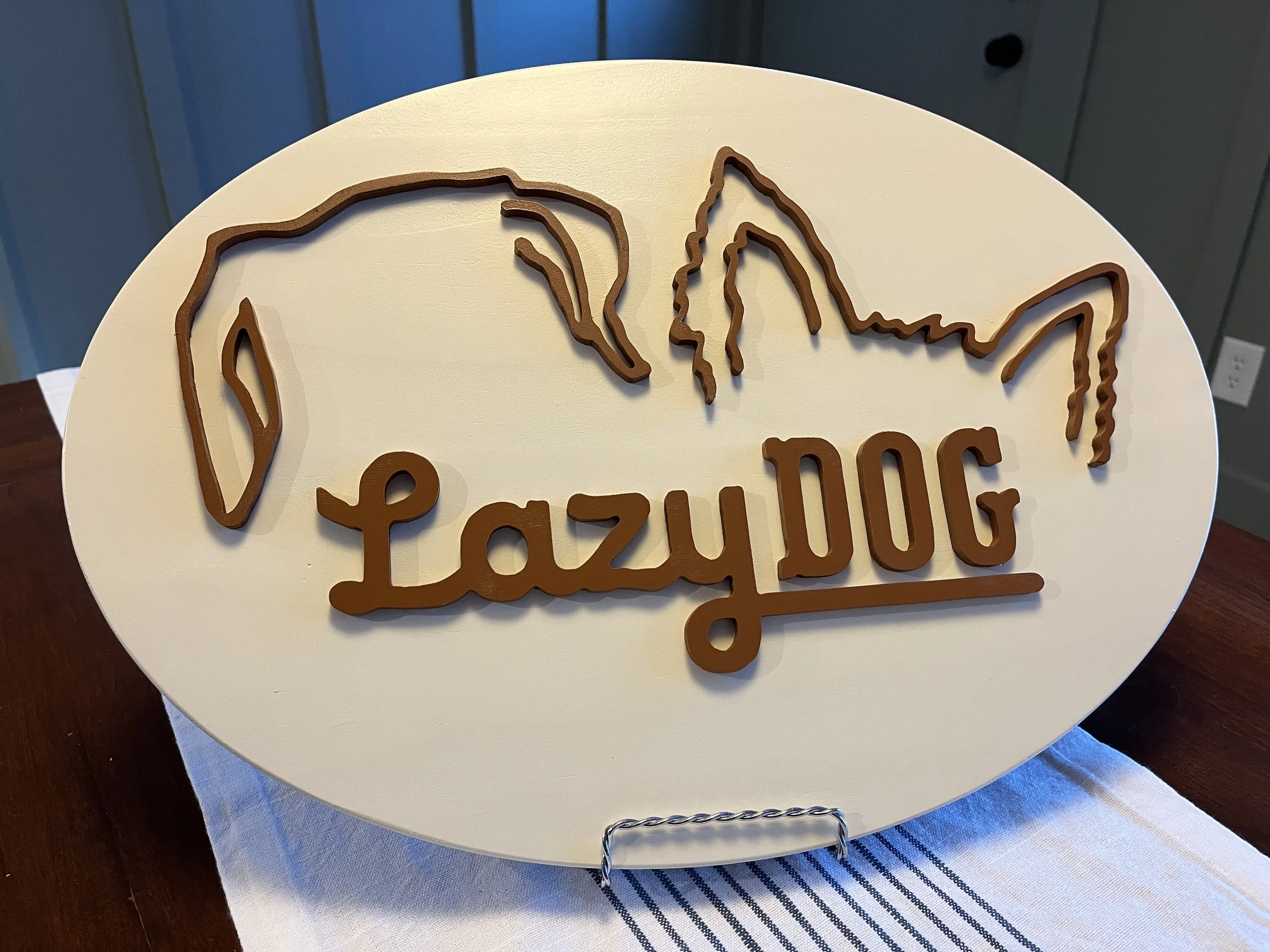Wooden sign with the outline of a dog's face and ears, with the text 'LazyDOG' written underneath.
