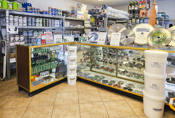 Display case with various small hardware and plumbing parts, including pipes, fittings, and blades, in a store aisle.
