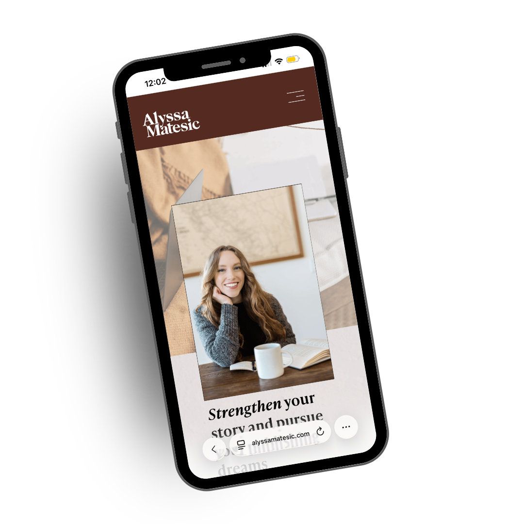 A smartphone displaying a website for Alyssa Matesic, featuring a woman with long wavy hair smiling, sitting at a table with a mug and an open book, and the text "Strengthen your story and pursue".