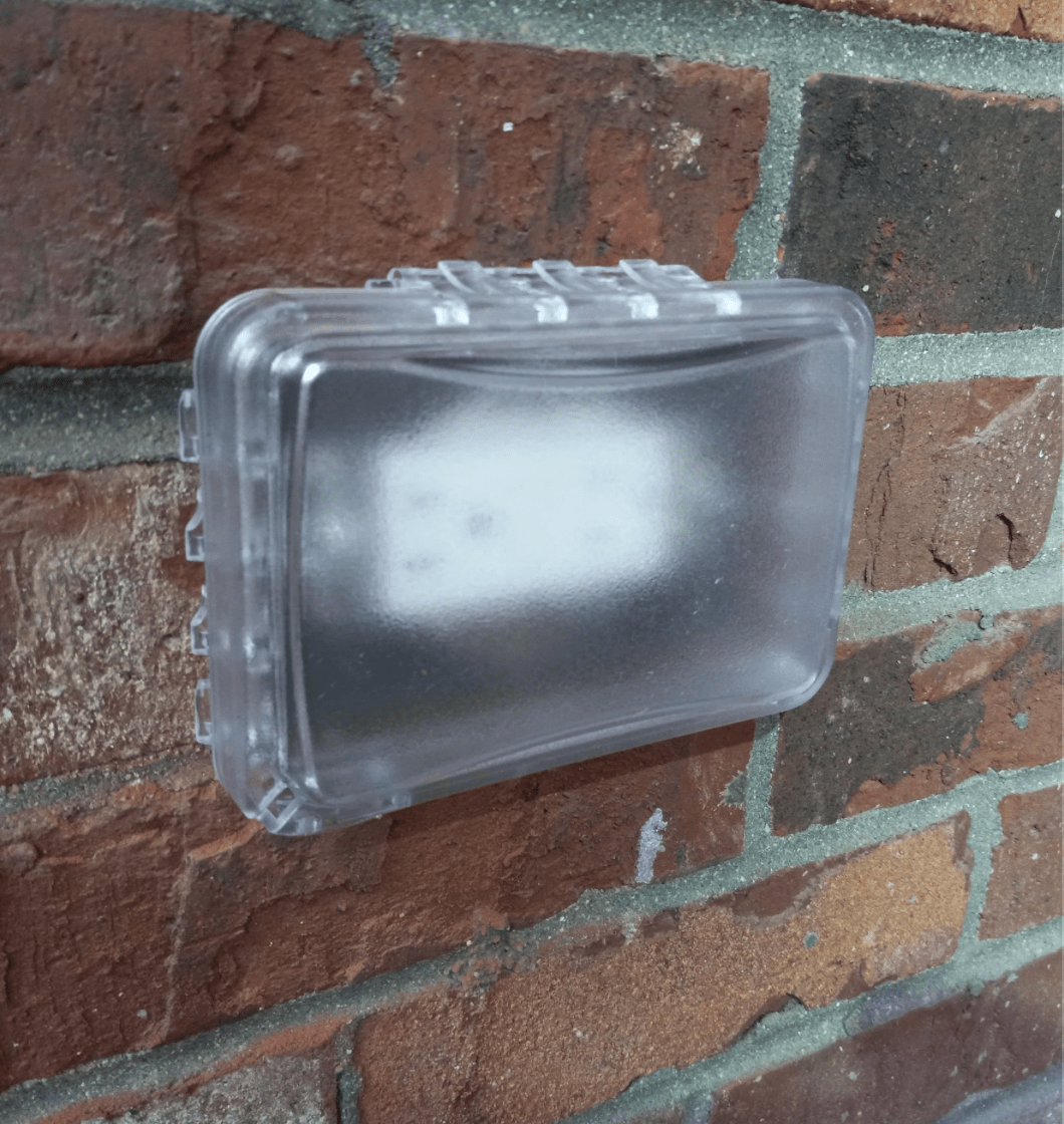 Close-up of a frosted glass light fixture mounted on a brick wall.
