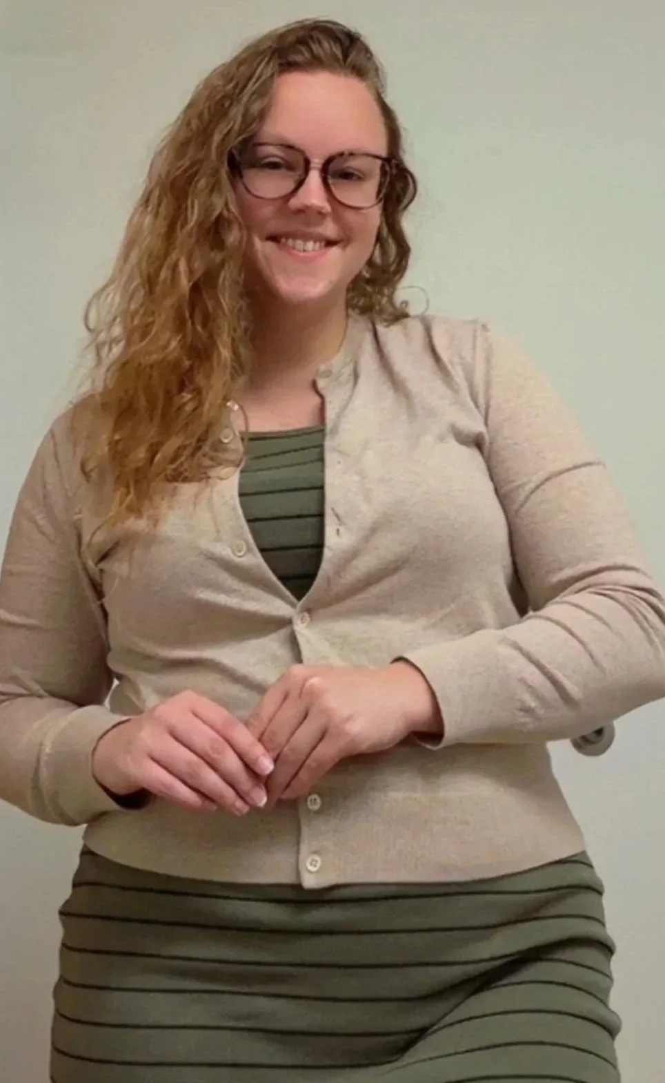 Birth doula Emily smiling wearing a green and black striped dress and neutral sweater