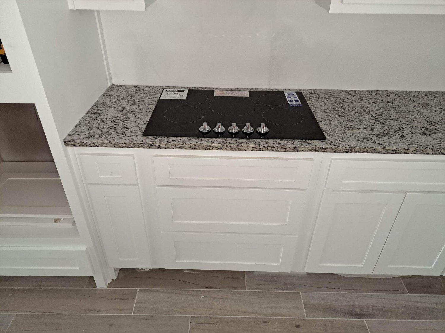White cabinets with granite countertops and a drop-in cooktop