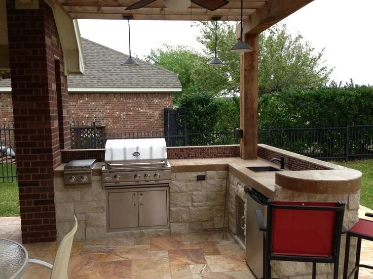 Outdoor kitchen island with stone countertop and built-in appliances