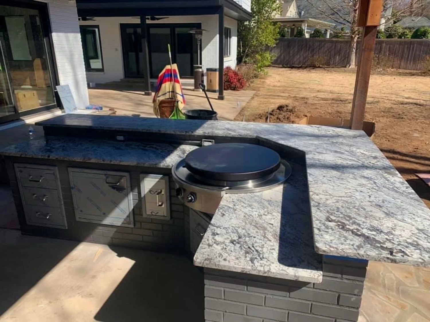 Stone bar top beside a pool deck with pergola posts